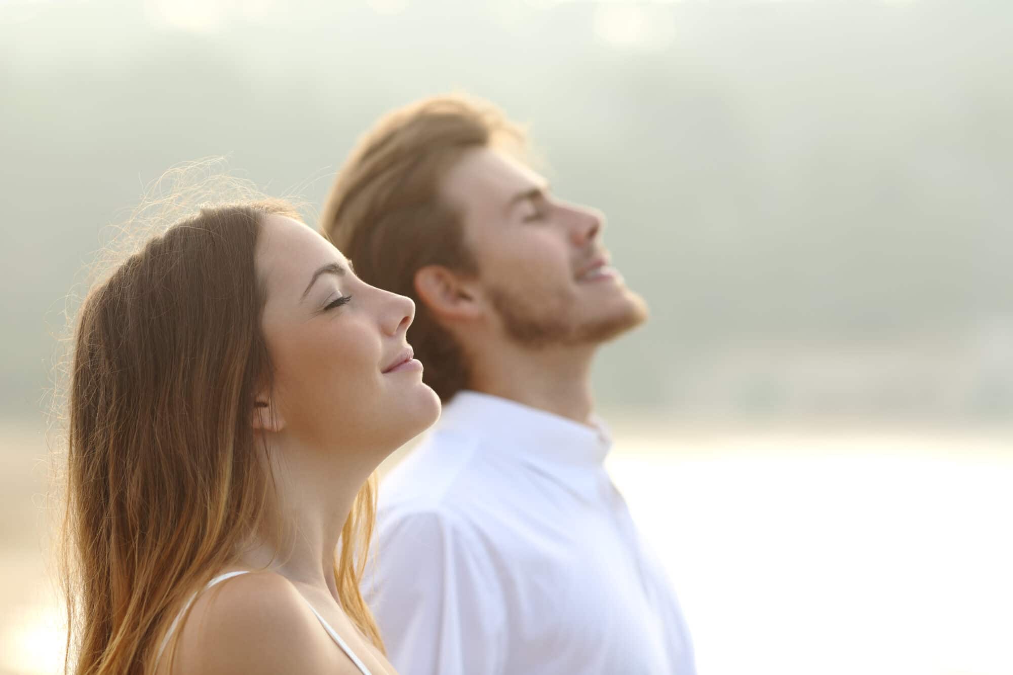 Profile of a couple of man and woman breathing deep fresh air together at sunset